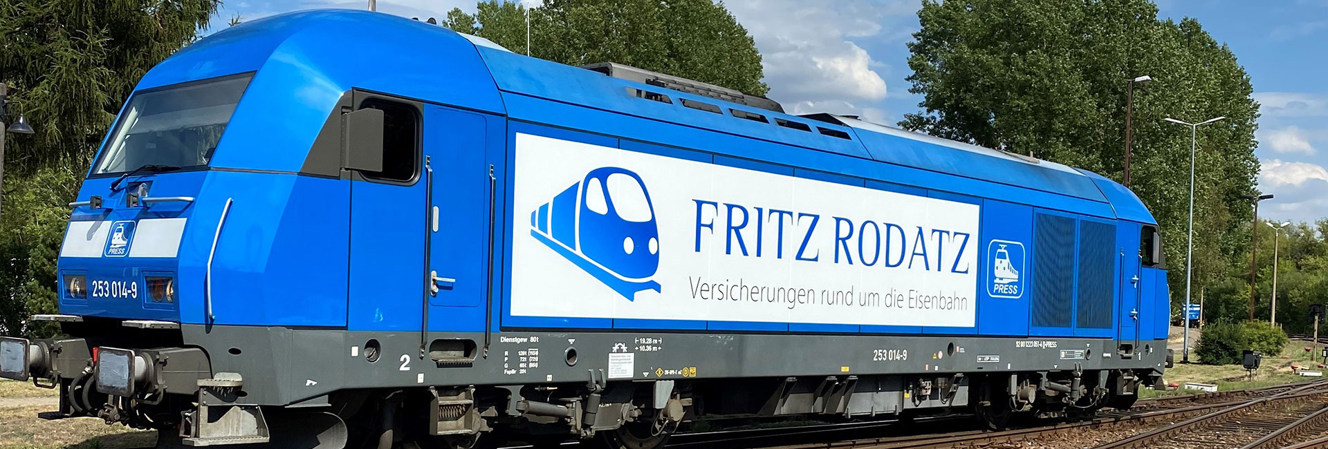 Blaue Lokomotive mit Fritz-Rodatz-Beschriftung auf einem Bahngleis